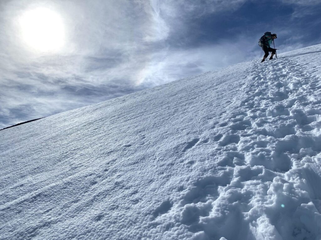 Kristen looks down at her tracks up a snowy mountain