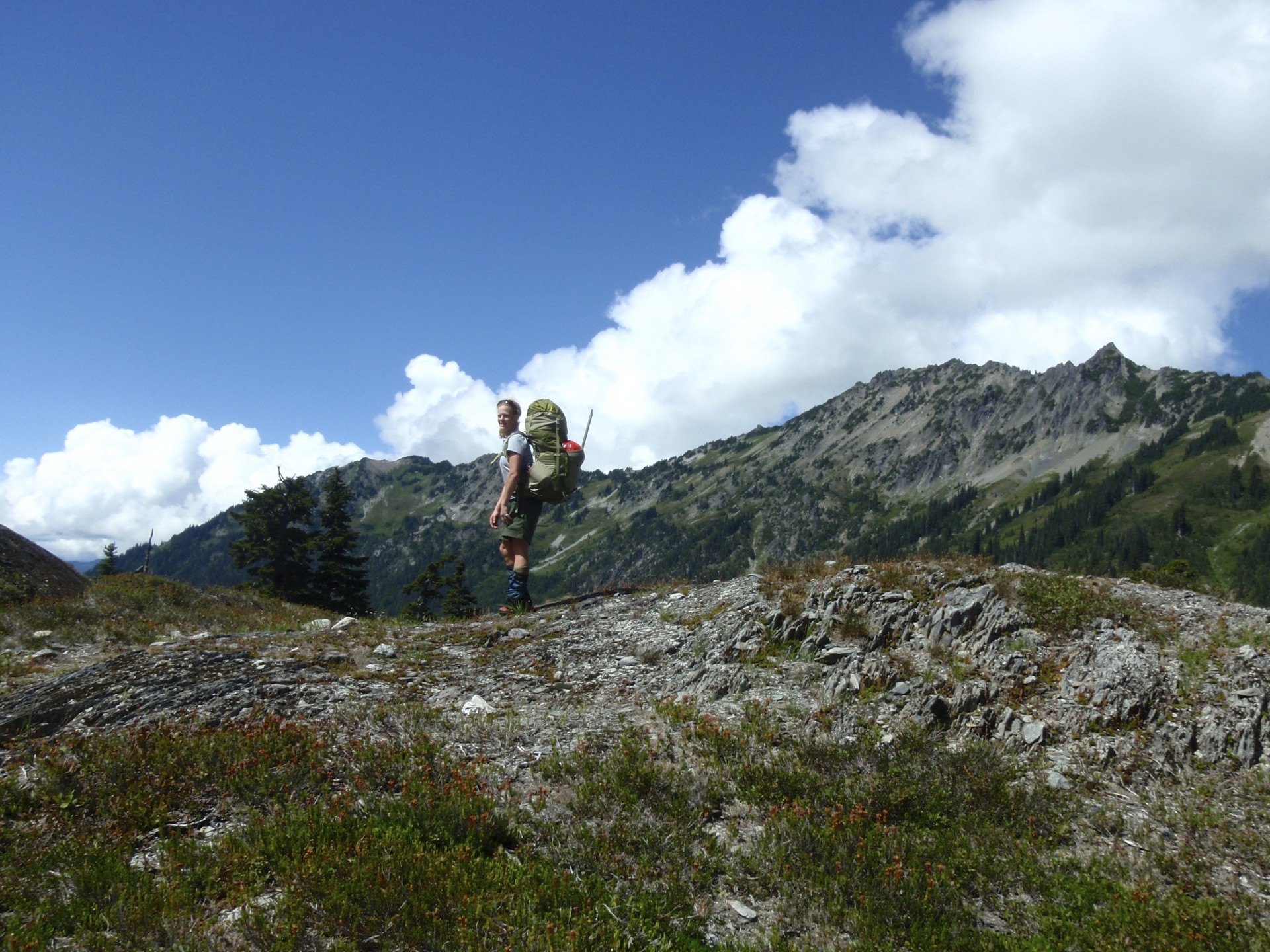 Nicole stands on a hill with her backpack on