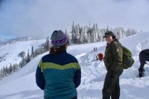 A park ranger speaks with a school teacher on a snow science field trip