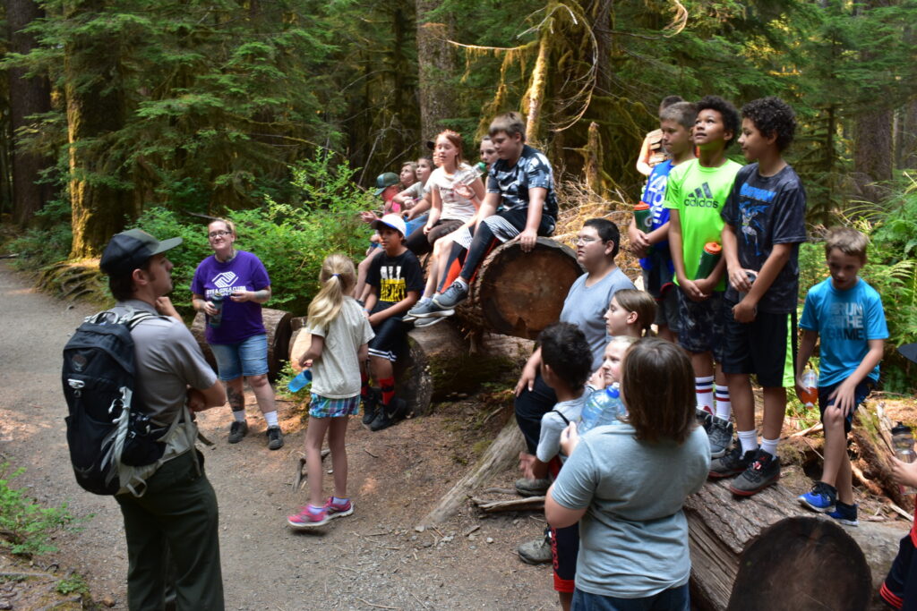 A student group learns from Dean while standing around fallen logs