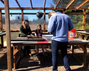 Mitch films a young volunteer as a ranger guides her on how to plant seedlings outside the Albright Native Plant Nursery