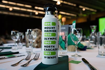 WNPF's water bottle featuring the anniversary years of each park, on a banquet table set with glasses and silverware