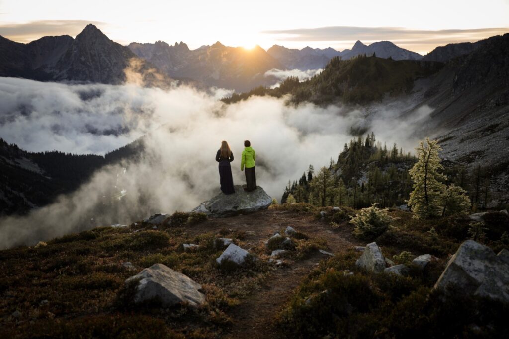 The musical mountaineers stand on a rock looking out over the clouds and peaks