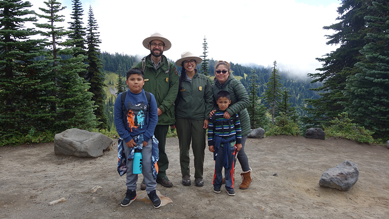 Rangers pose with youth participants on a trail