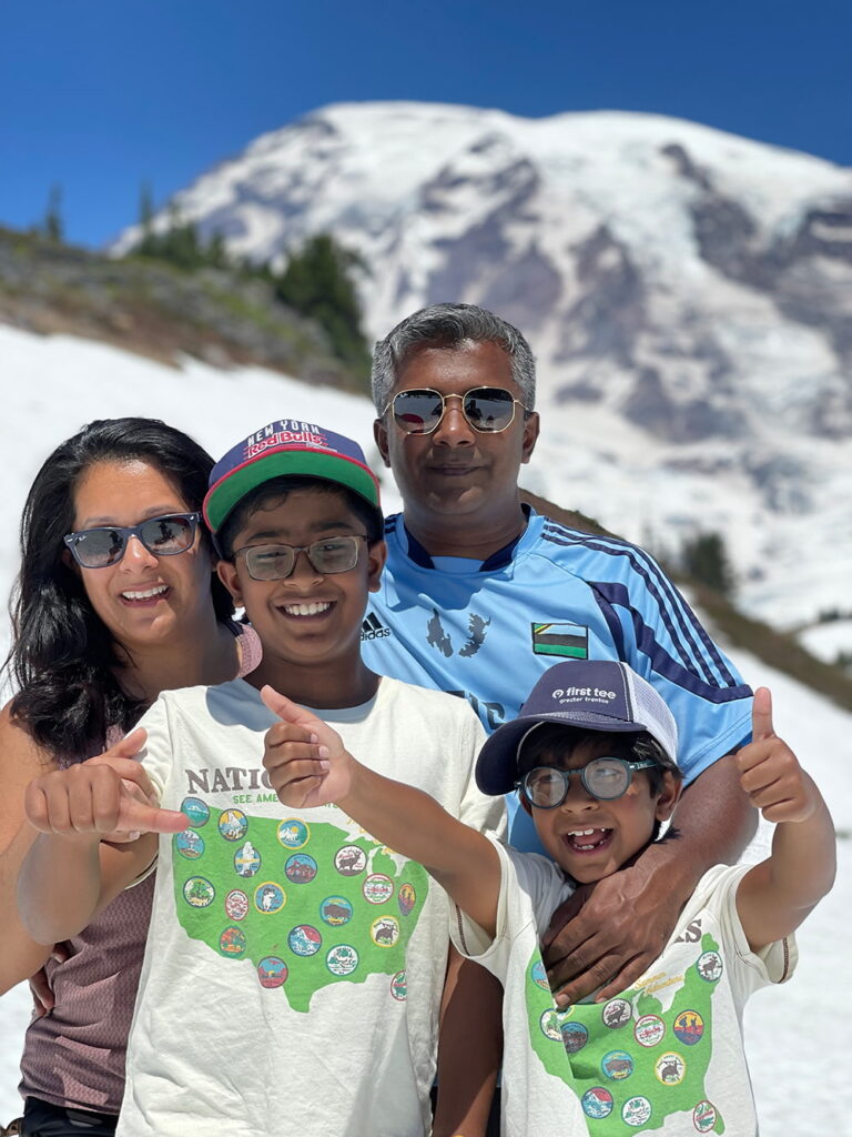 The Keshodkars smile in front of a snowy Mount Rainier