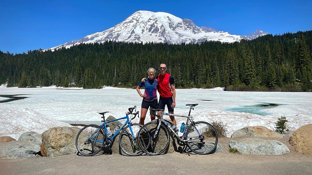 Kristen and friend pose with bikes in front of Mount Rainier at Reflection Lakes