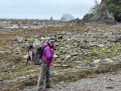 Andrea stands on the Olympic coast with her backpack