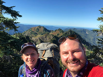 Andrea and her husband smile on High Divide in Olympic National Park