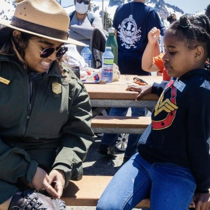 Image of a park ranger sitting with a young park visitor of Mount Rainier