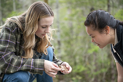 A student shows a NPS intern an insect she found in the garden