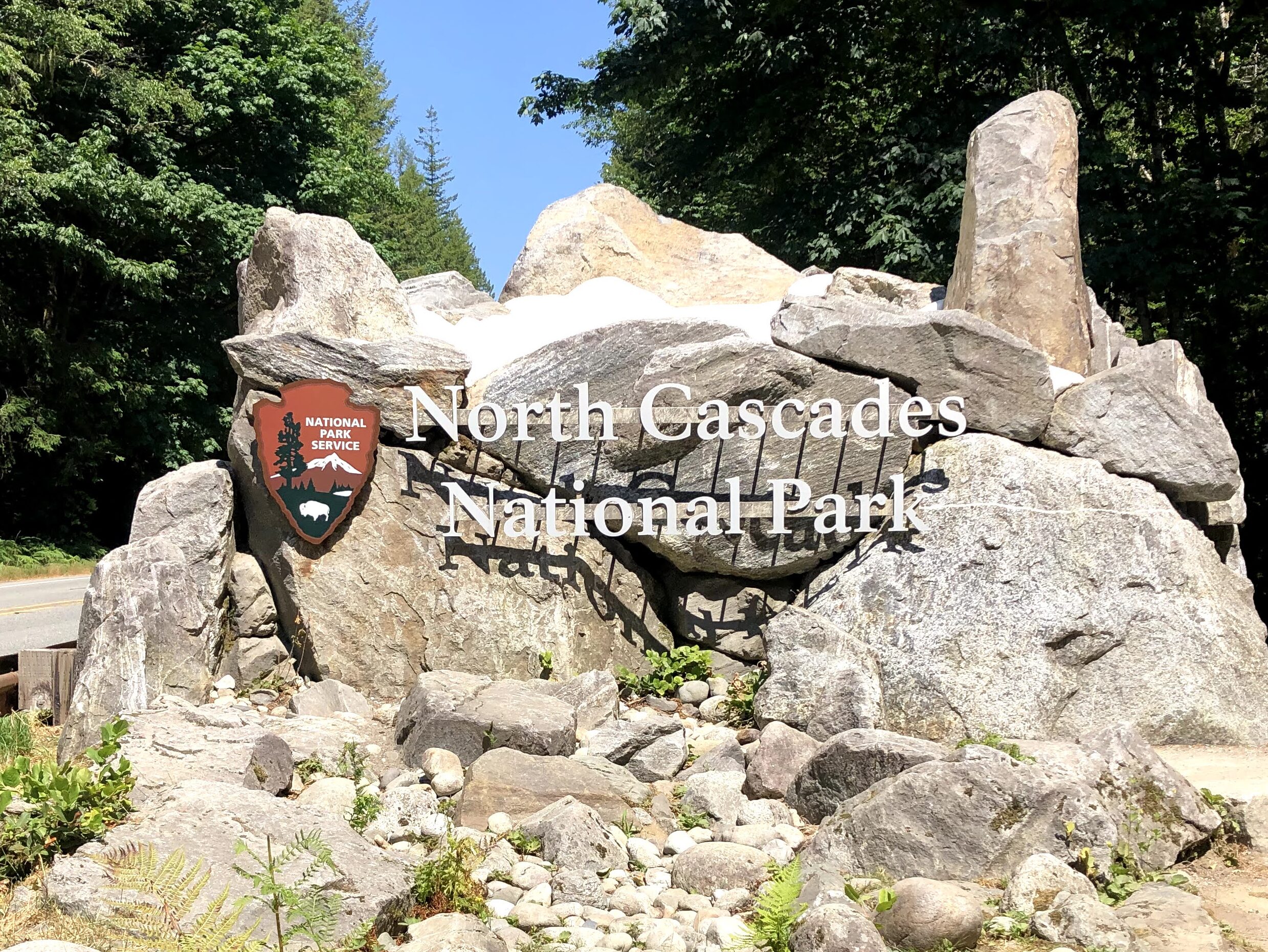 Photo of an entrance sign that reads "North Cascades National Park" with rocks in the background.