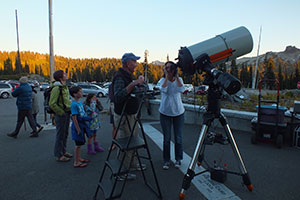 A night skies volunteer helps a visitor peer into the telescope