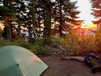 A tent at a campsite with a view of sunset.