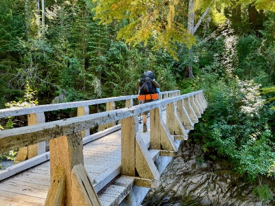 hiker crossing a wooden bridge