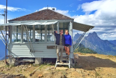 Two people standing outside of a fire lookout.