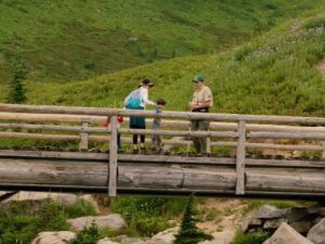 Man, woman, and child standing on a wooden bridge.