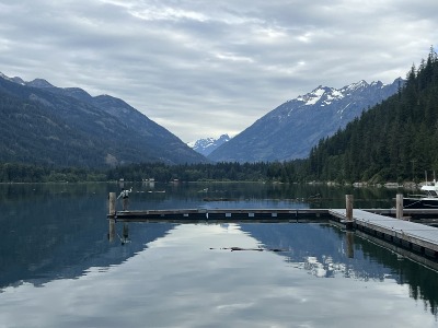 A lake view with a boat dock and mountains in the back.
