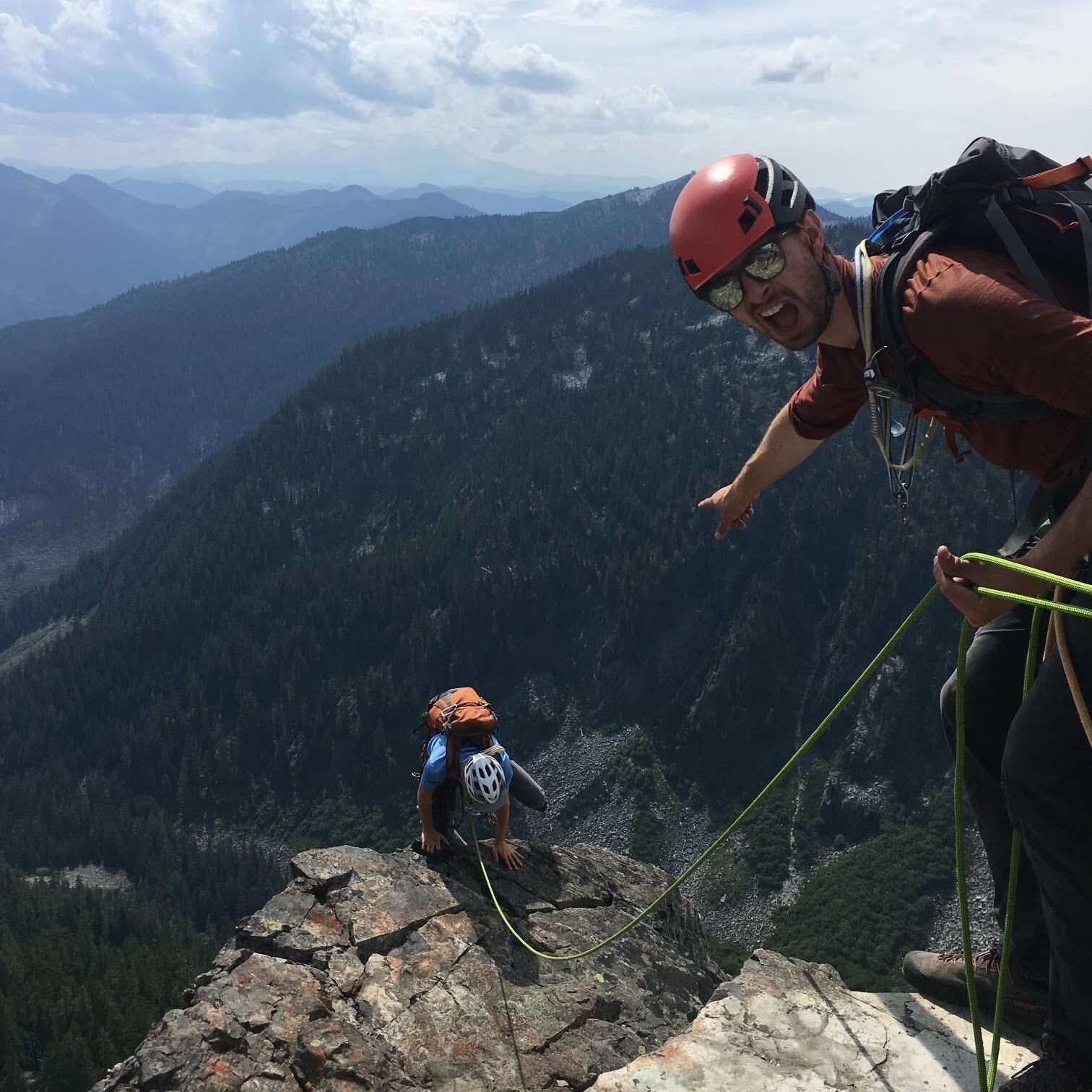 Two climbers on a rocky mountain with helmets and climbing gear.