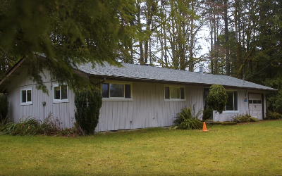 A long gray house surrounded by trees.