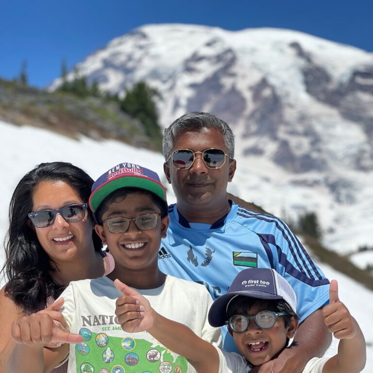 Family of four, mother, father, and two sons standing in front of Mount Rainier. 
