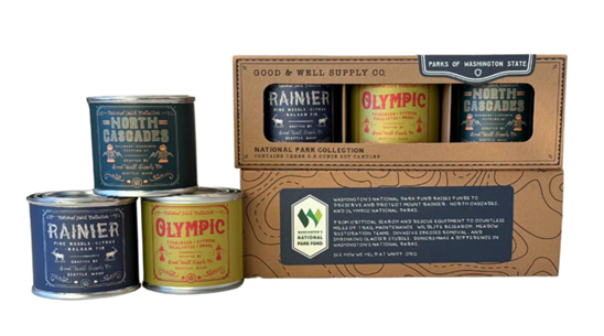 a box filled with three candles inside and three candles stacked next to it reading "Rainier, Olympic, North Cascades"