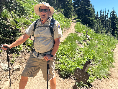 A man standing in the middle of a trail wearing hiking gear and holding poles.