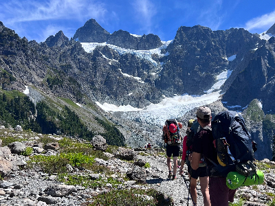 a group of climbers looking at a glaciated, rocky mountain.