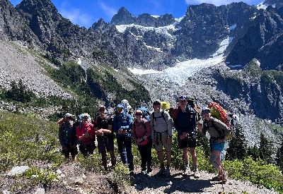 7 people standing in front of a mountain with large backpacks on