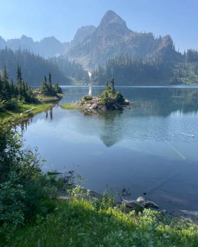 A photo of a clear blue lake with montains in the background with blue skies.