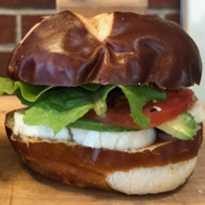 a photo of a brioche sandwich with lettuce, tomato, and cheese