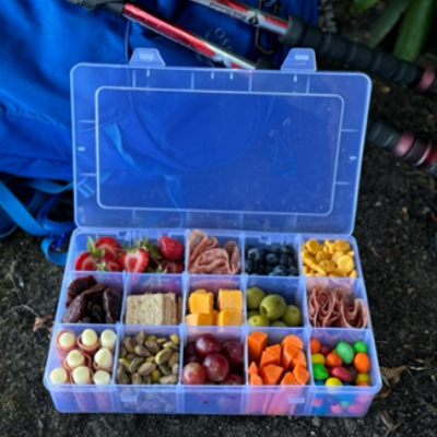 A tackle box filled with cheese, meats, and candy