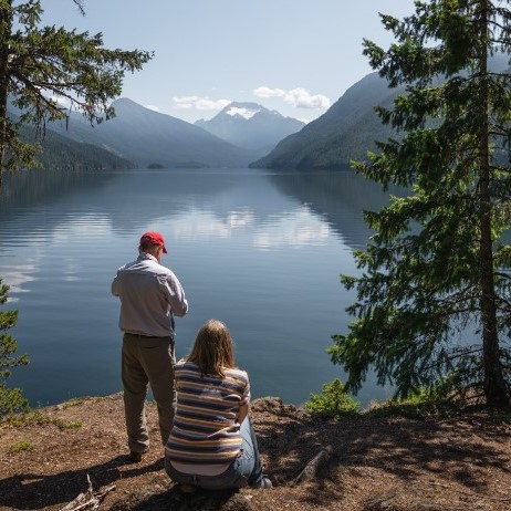 Two people looking at a lake with mountains in the background.