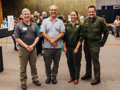 Three park superintendents and WNPF's CEO stand for a photo, smiling during an event at a store.